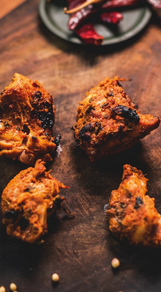 Northampton's best Punjabi Street Food, Takeaway and Delivery Chicken Tikka on a wooden board garnished with chilli